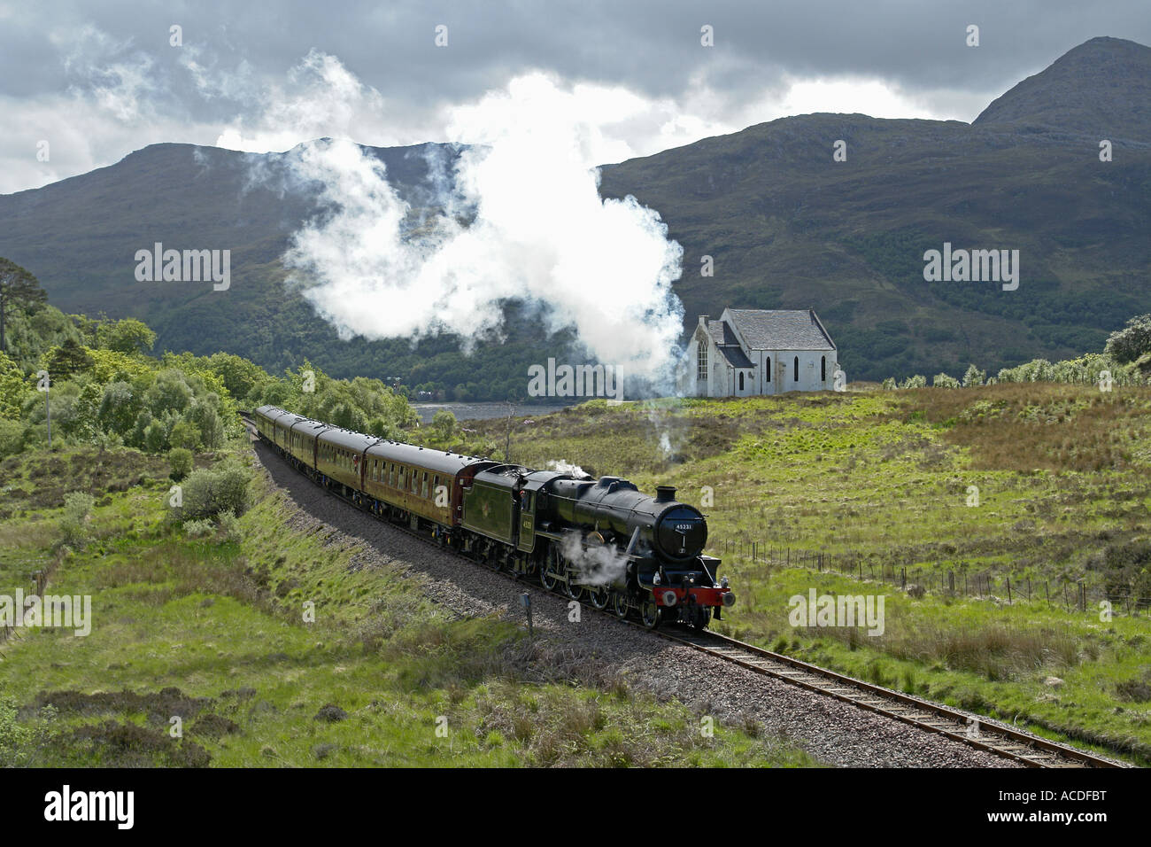 Tren de vapor operados por Ferrocarriles de la costa oeste haciendo su camino hacia Mallaig pasando la iglesia cerca de Lochailort Foto de stock