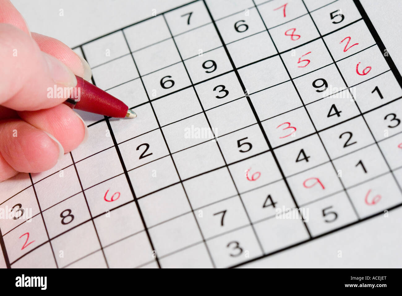 marioneta Embotellamiento Diez Mano sujetando una pluma roja resolver un Sudoku puzzle número japonés  Fotografía de stock - Alamy