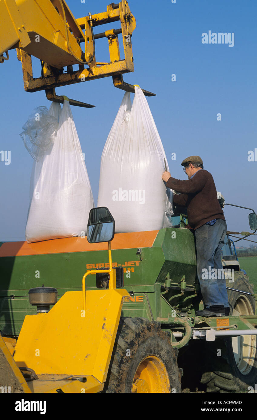 Conductor del tractor llenando Amazone tolva con fertilizante a partir de dos mini bolsas Foto de stock