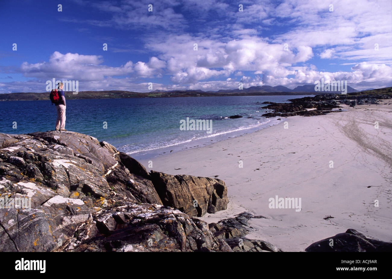 Caminante mirando por encima de una playa de arena en la orilla de la Bahía Mannin, Connemara, Condado de Galway, Irlanda. Foto de stock