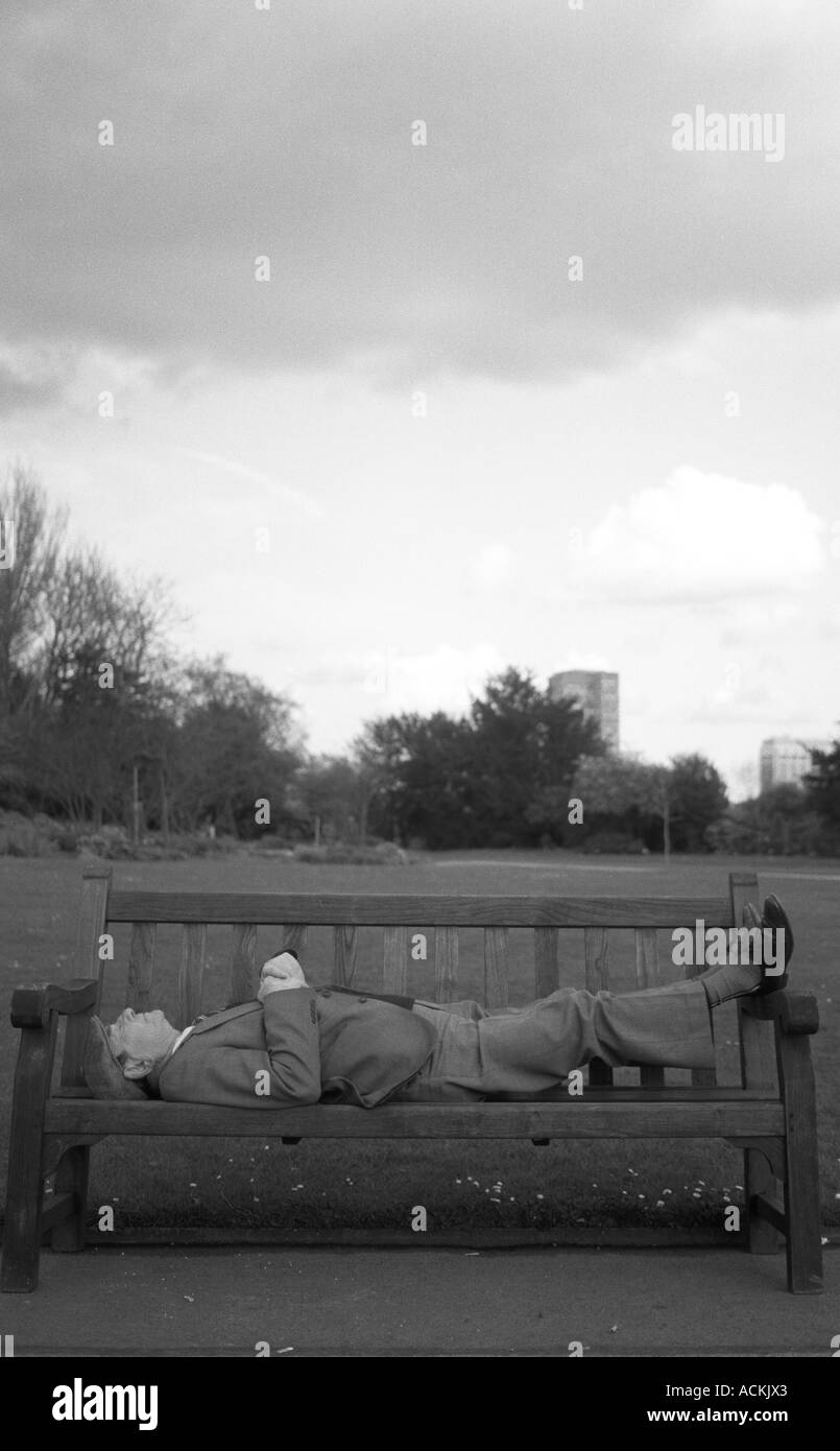 Un anciano señores durmiendo en una banca del parque en un día de invierno, St Mary's Rose Garden, Regents Park, Londres, Reino Unido. Foto de stock