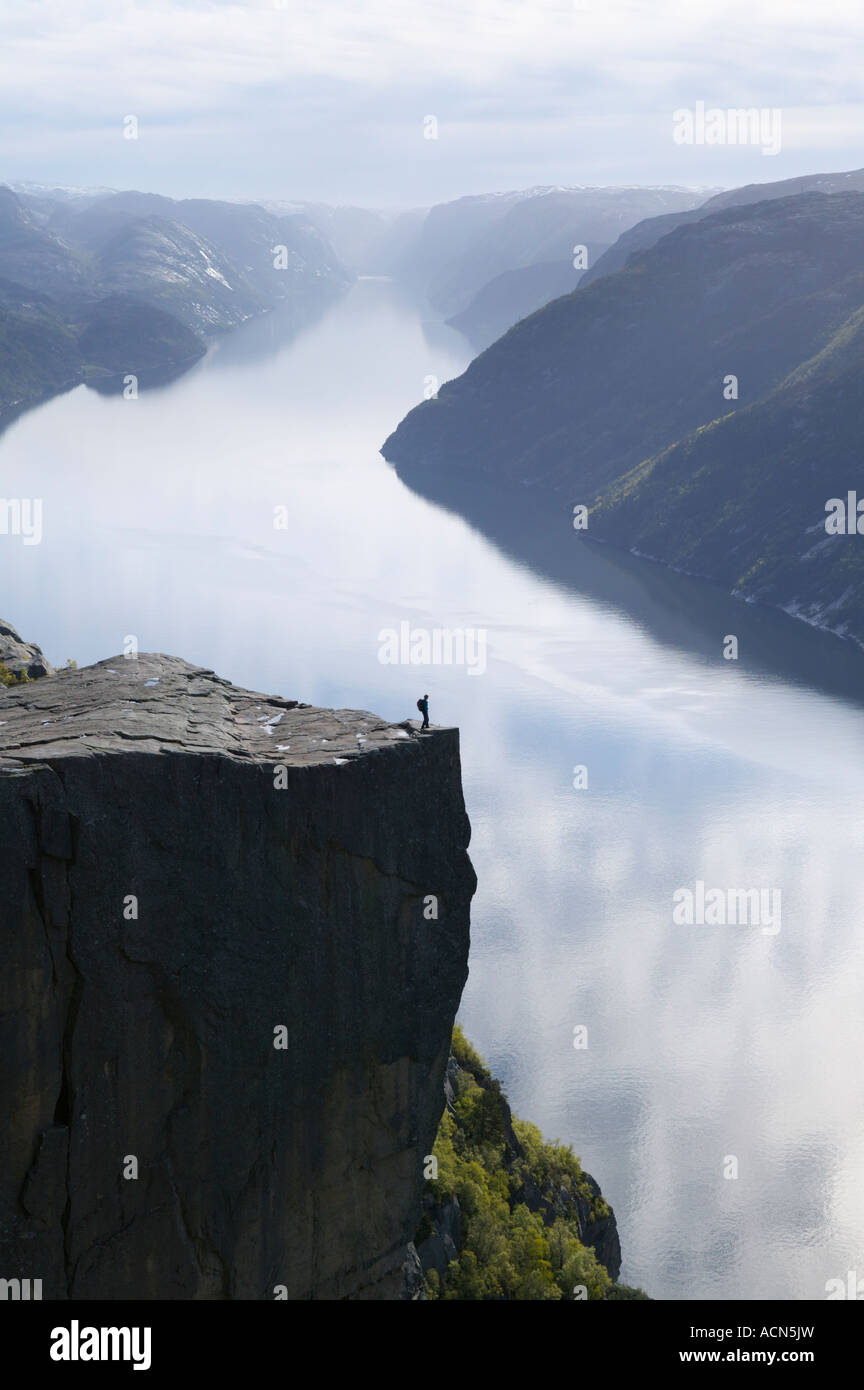 Walker de pie en Preikestolen, o roca púlpito, sobre Lysefjorden, Forsand, Rogaland, Noruega. Foto de stock
