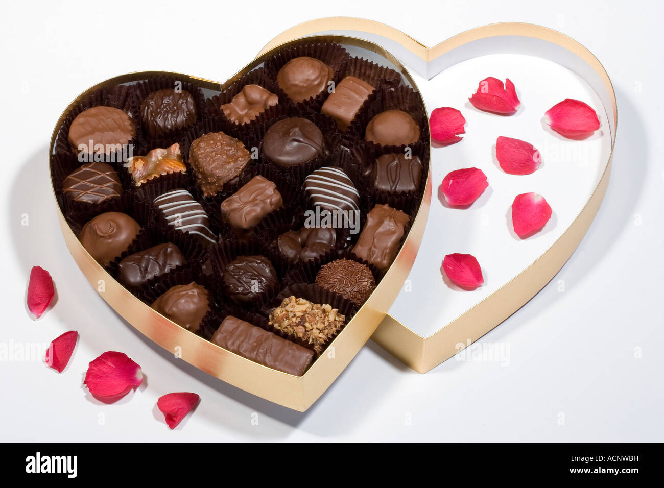 Día de San Valentín regalo de una caja de oro en forma de corazón de dulces  de chocolate con pétalos de rosa roja dispersos Fotografía de stock - Alamy