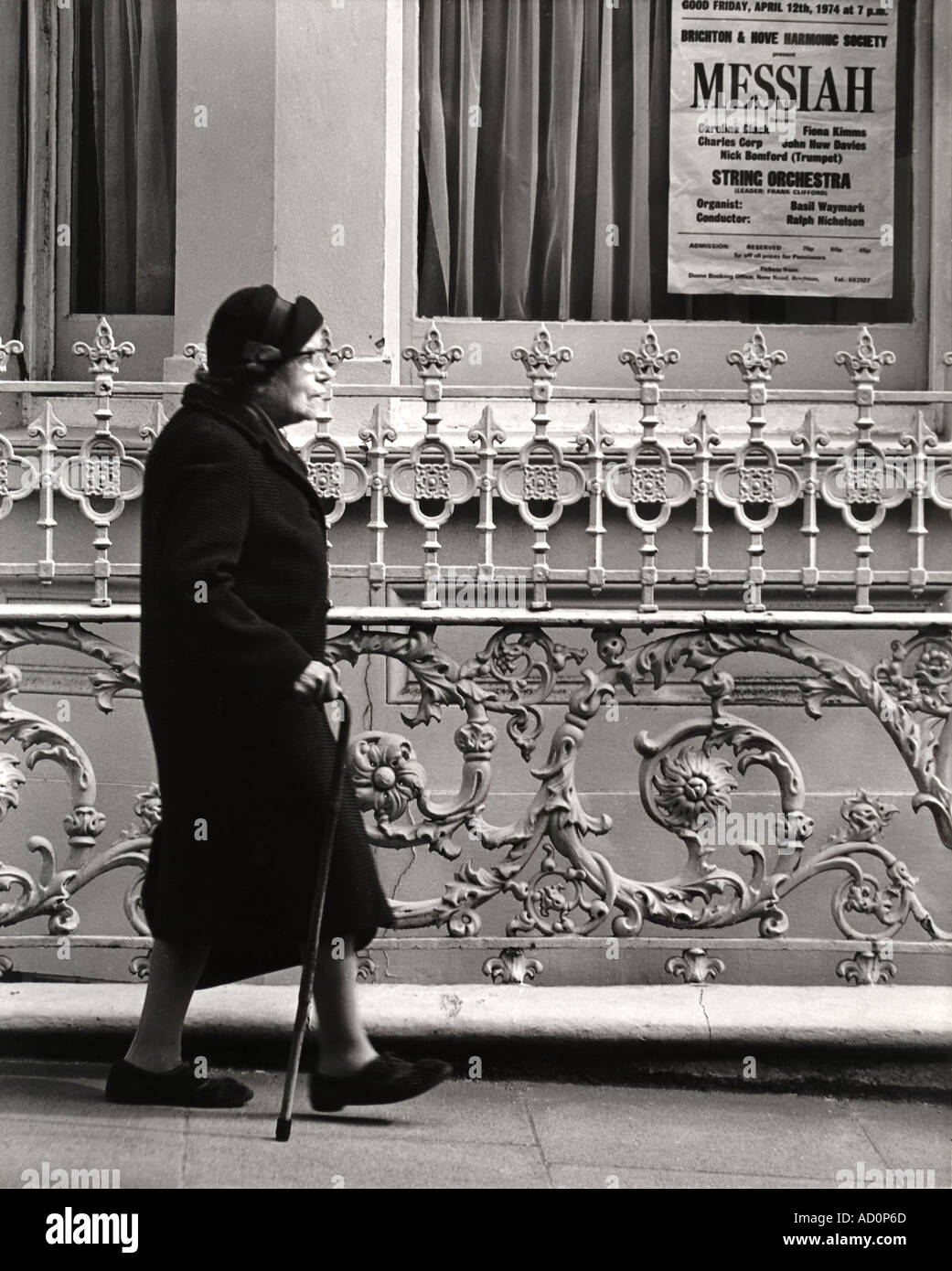 Anciana caminando con bastón delante de la barandilla de hierro. Foto por John Gay, Londres, Inglaterra, a mediados del siglo XX. Foto de stock