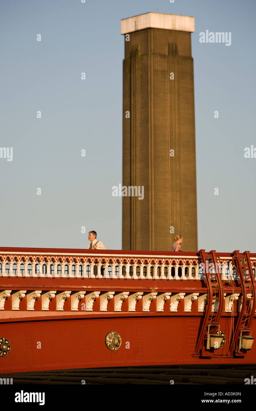 Un hombre y una mujer, cruzando el puente de Blackfriars con el Tate Modern chimenea en el fondo. Foto de stock