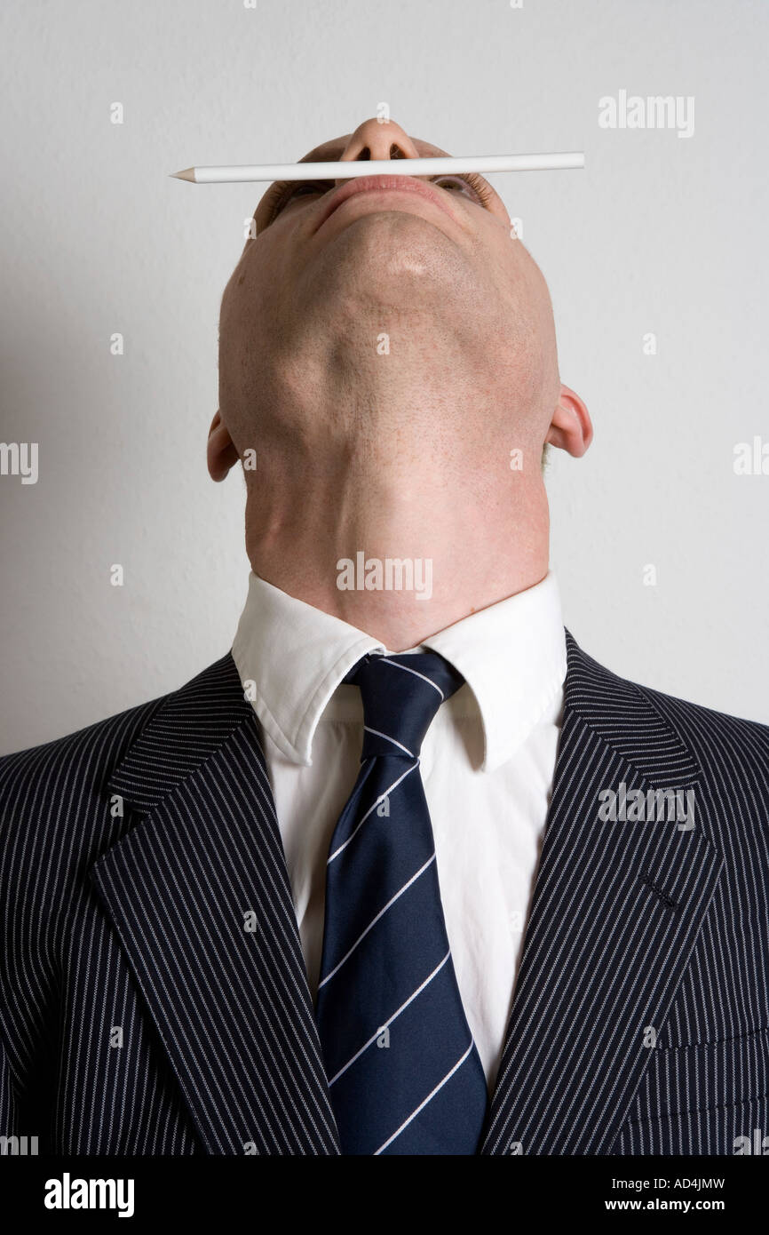 Un empresario de balancear un lápiz entre su nariz y sus labios Foto de stock