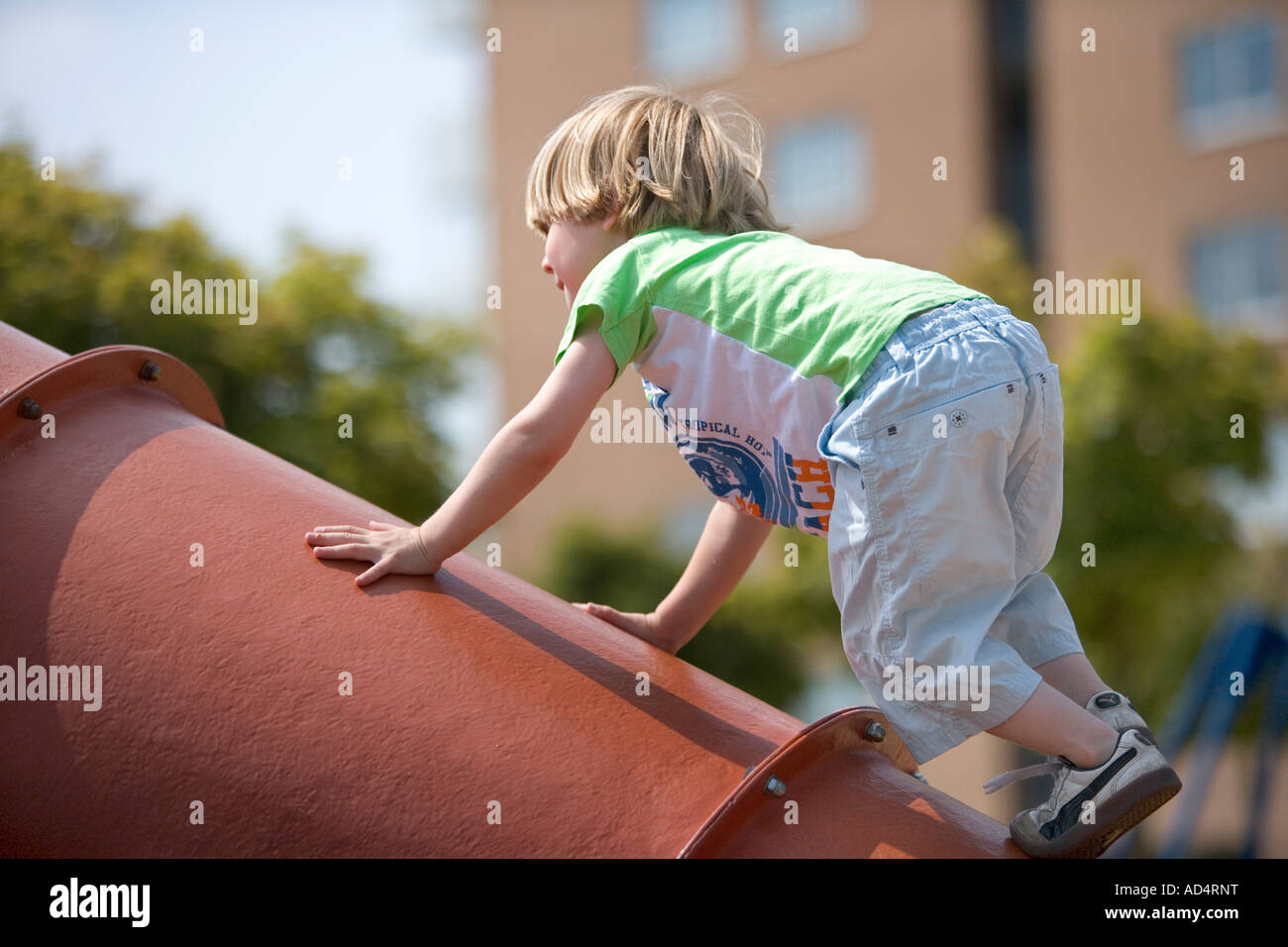 Boy escalada en un tubo de hierro en el patio Foto de stock