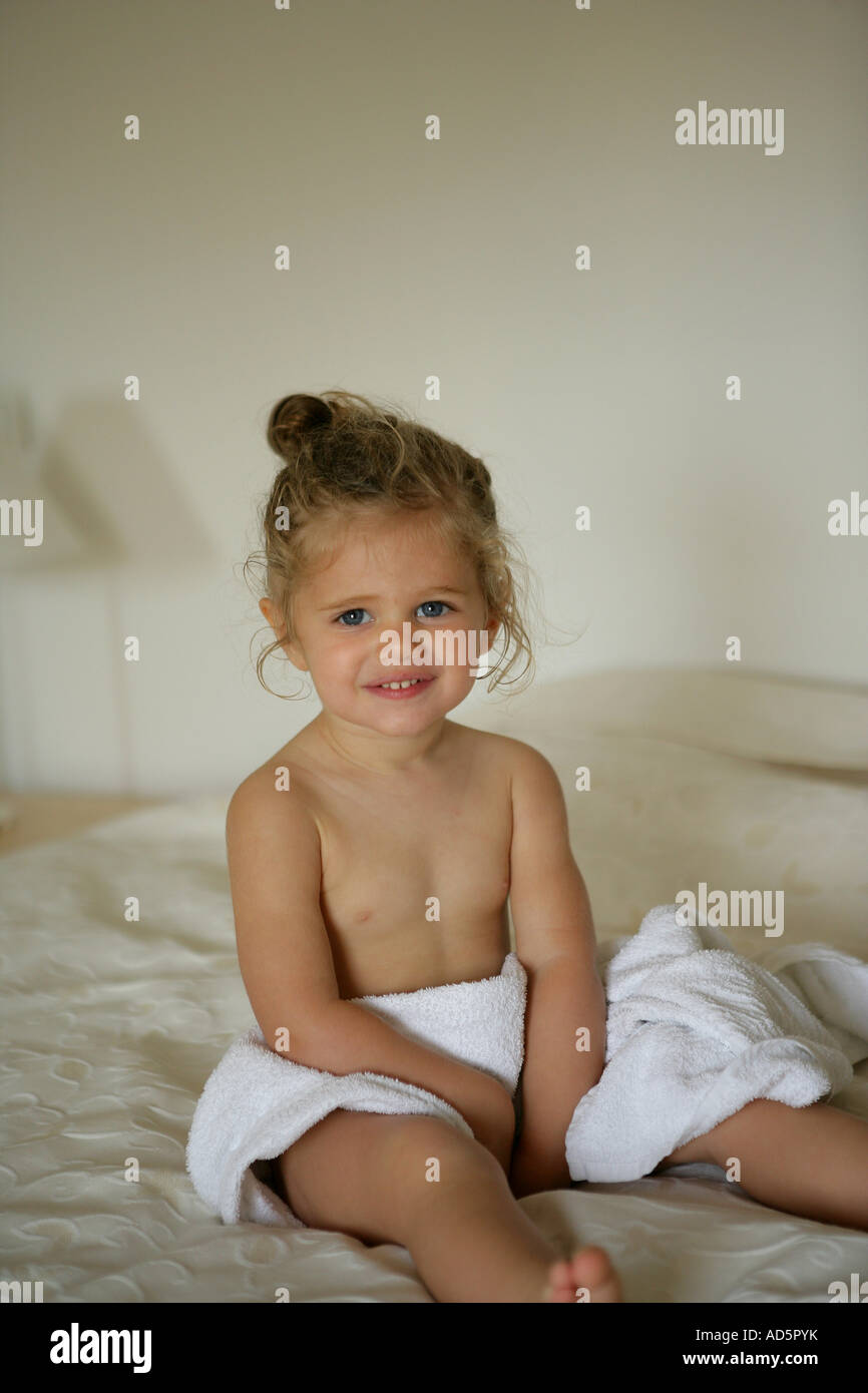 Niña con una toalla de baño sentado en una cama Fotografía de stock - Alamy