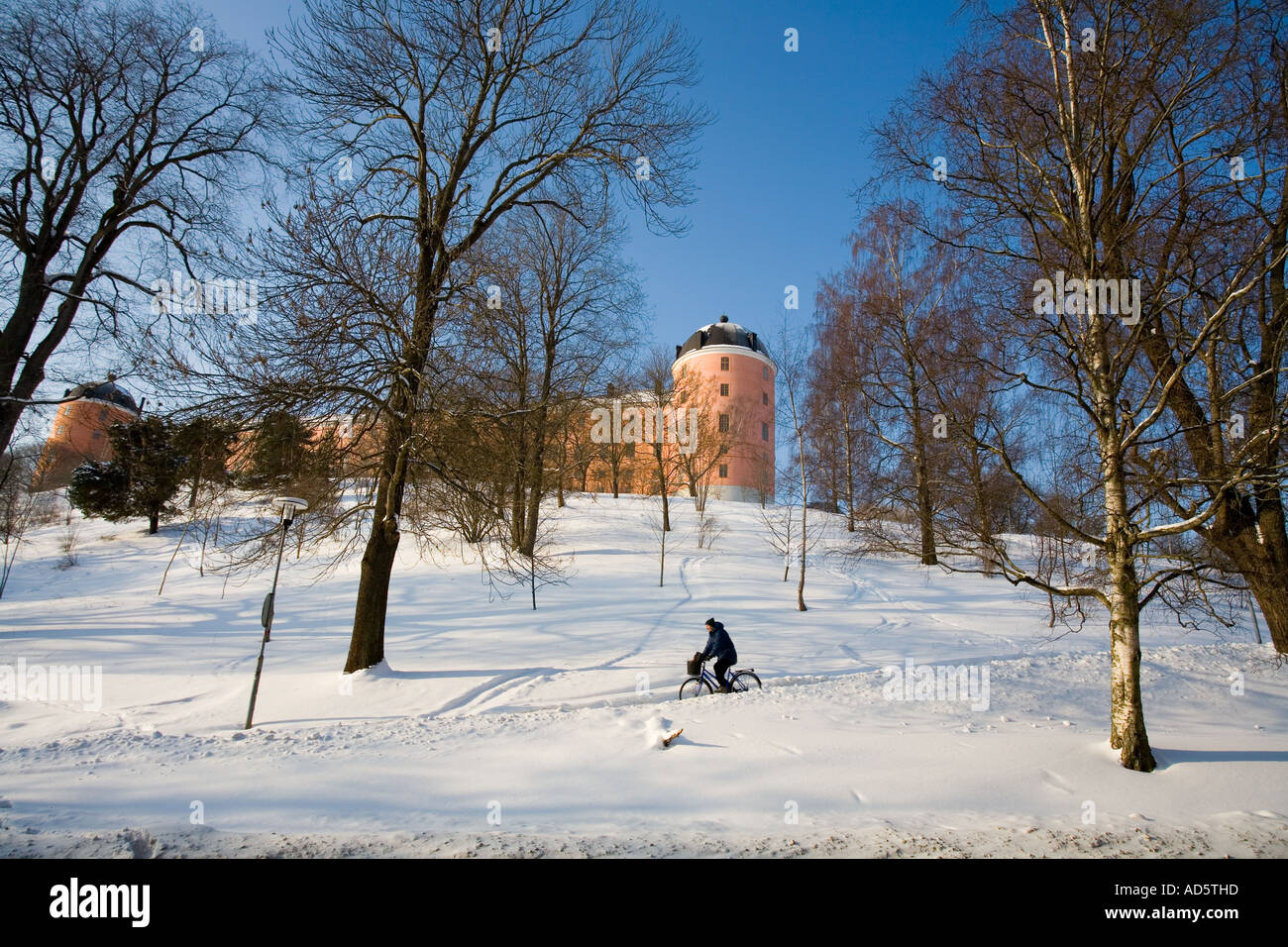 Castillo del siglo XVI de Uppsala, Suecia, dependiente de la nieve, sol brillante con ciclista Foto de stock