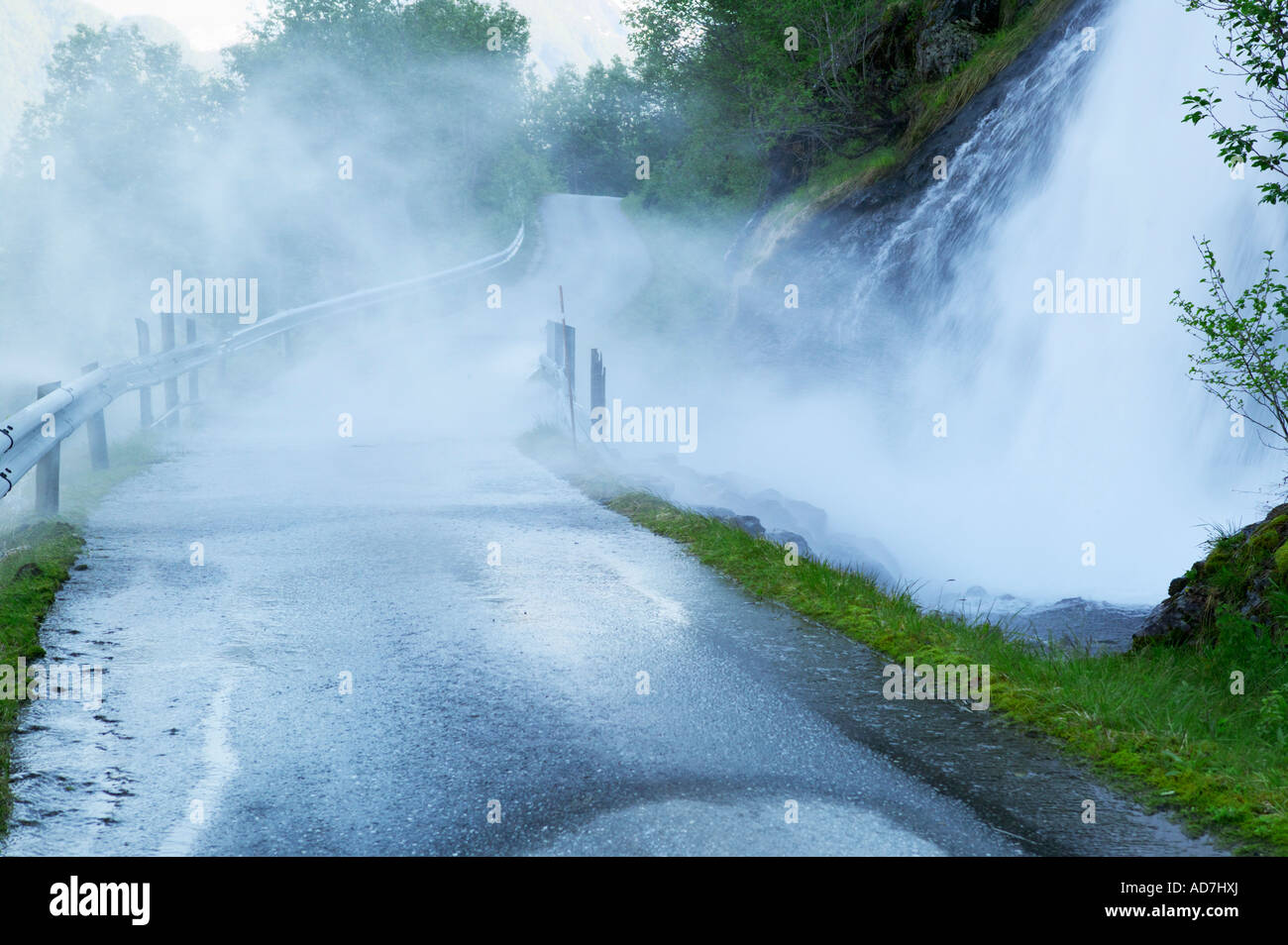 La pulverización de una cascada a través de una carretera rural Fjaerland Sogndal Noruega Sogn og Fjordane Foto de stock