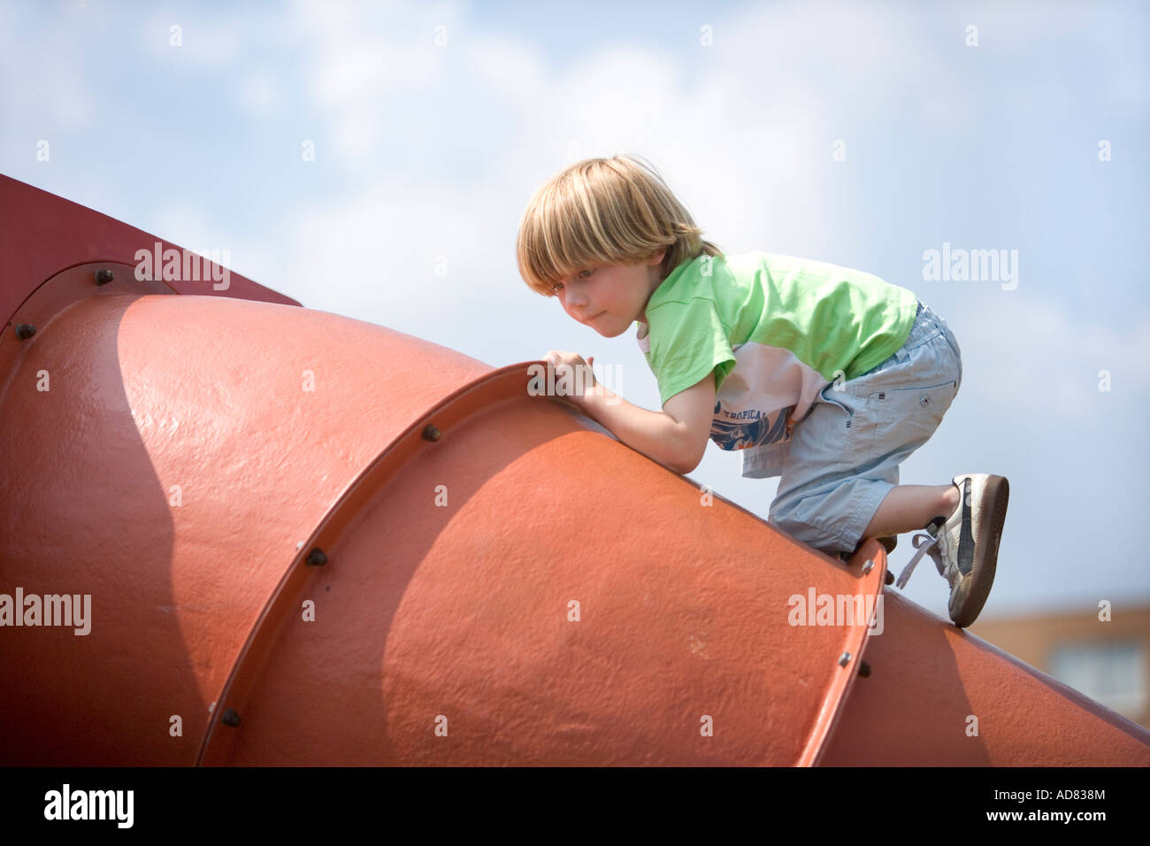 Boy escalada en un tubo de hierro en el patio Foto de stock