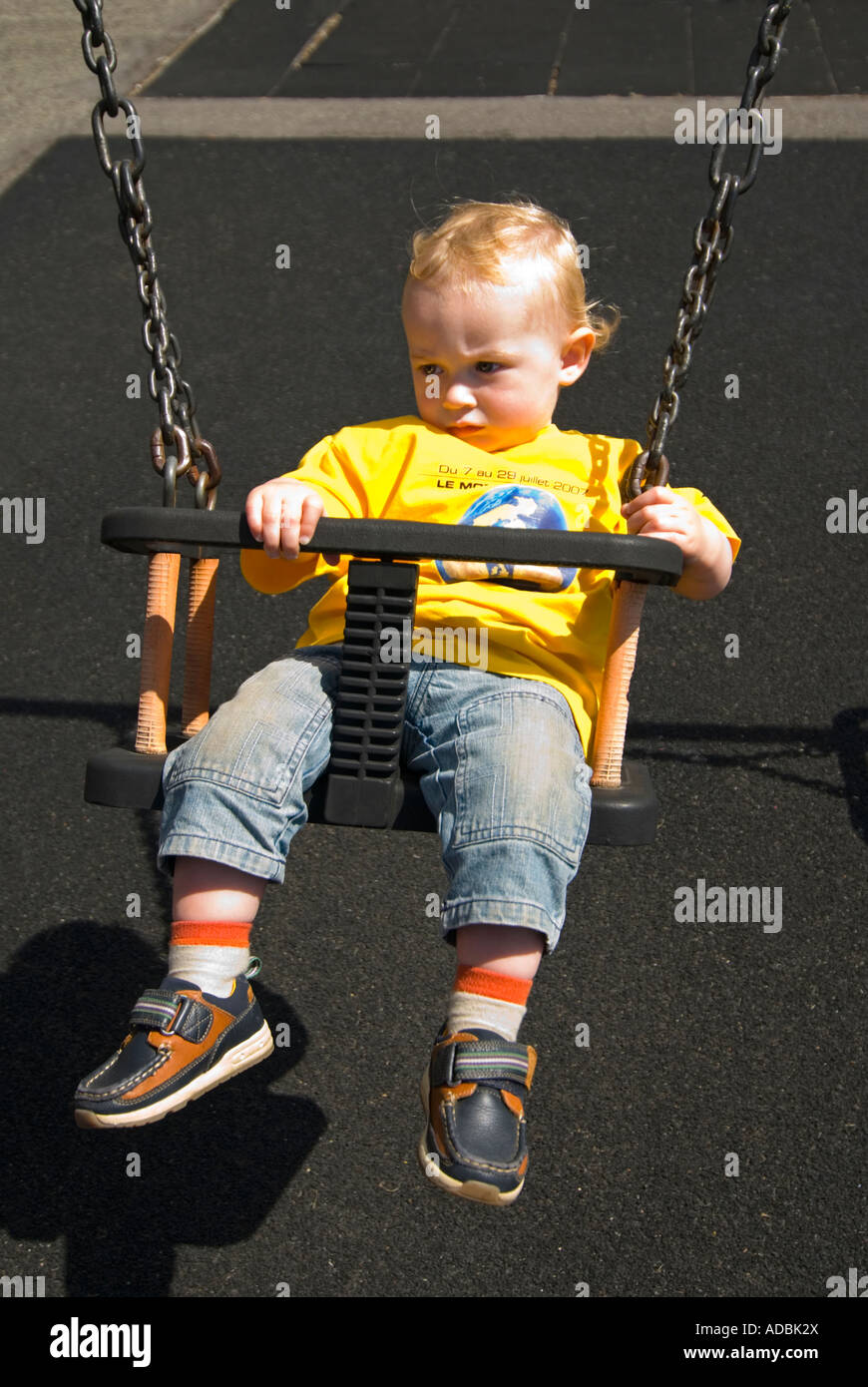 Vertical cerca de retrato de un tenue 16 mes de edad Baby Boy cansados después de ser empujada en los columpios en un parque Foto de stock