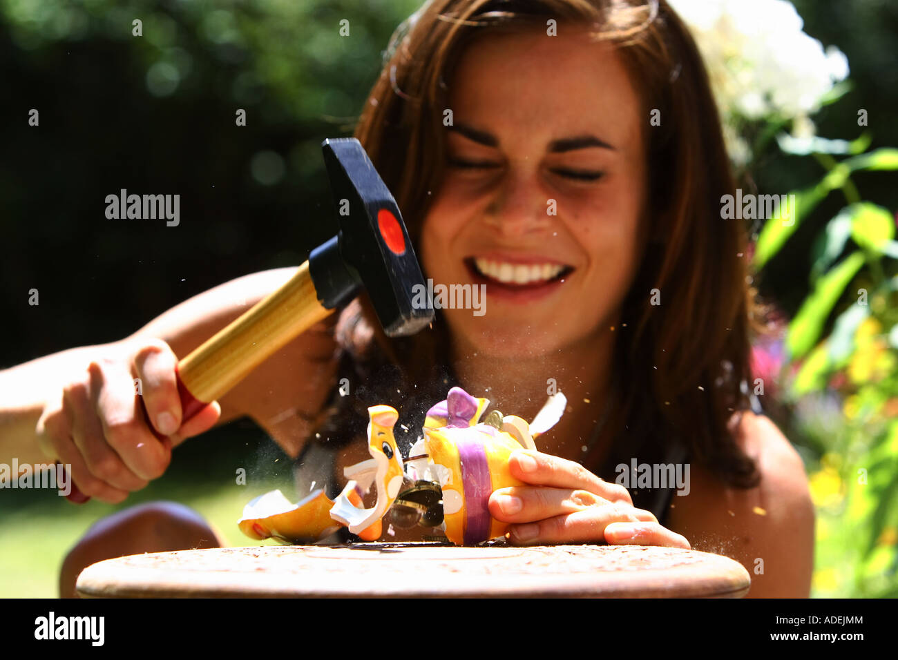 Mujer joven está robando una alcancía con un martillo © Peter Schatz/Alamy Foto de stock