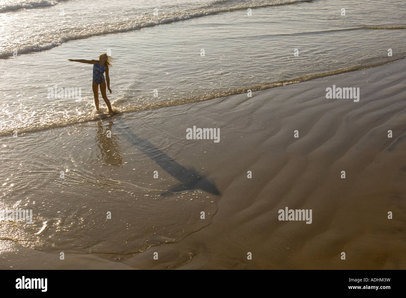 Una joven baila en el agua en la playa en California Foto de stock