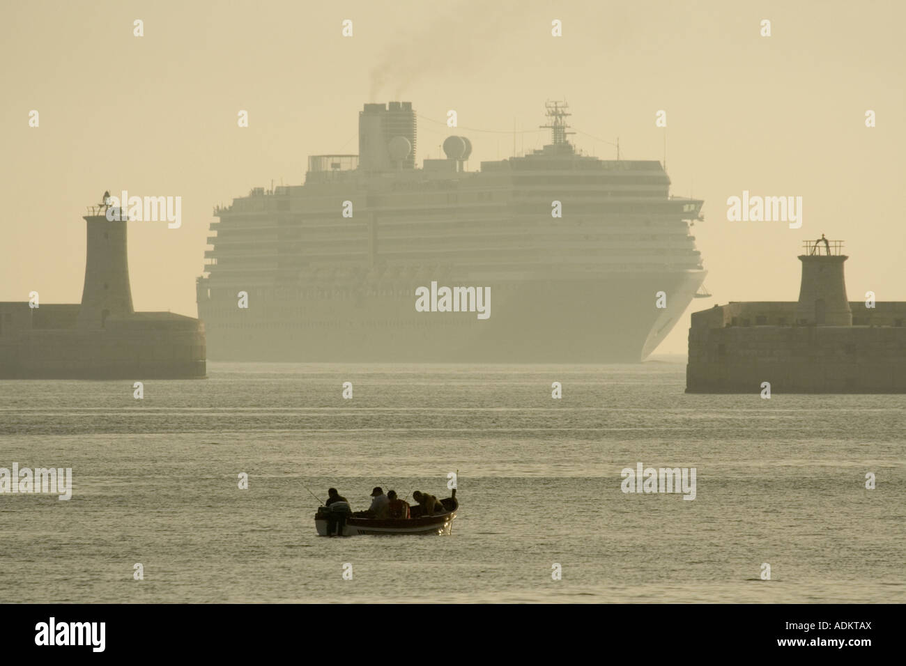 Viajes y turismo mediterráneo. Un crucero o camisas a punto de entrar en el gran puerto de Malta en la neblina del amanecer, con un barco pesquero en primer plano Foto de stock