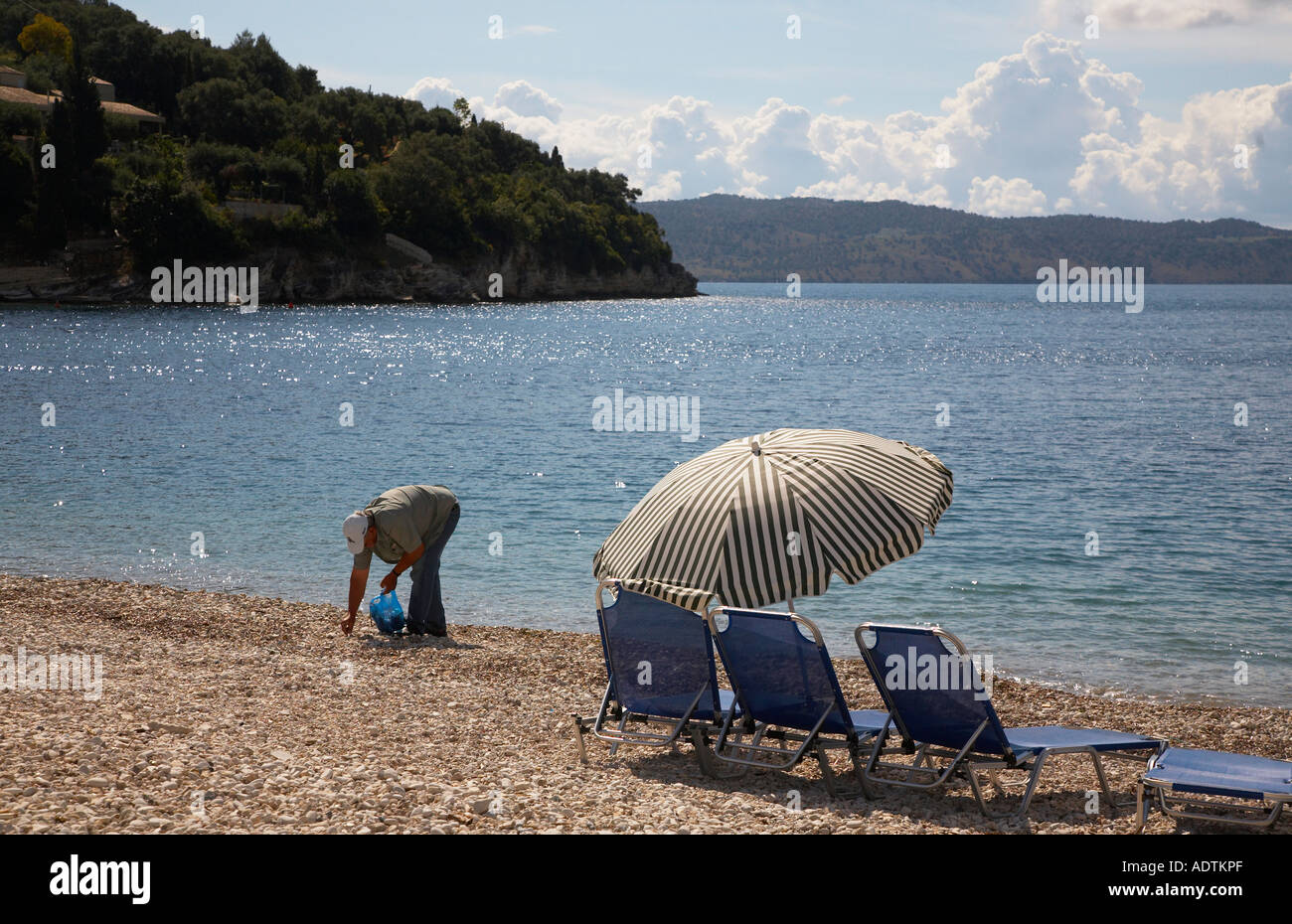 Un hombre tidies camada desde la playa en Kalami Corfu Foto de stock