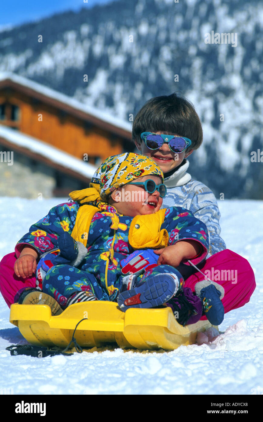 Los niños tobagganing, llevar gafas de sol Foto de stock