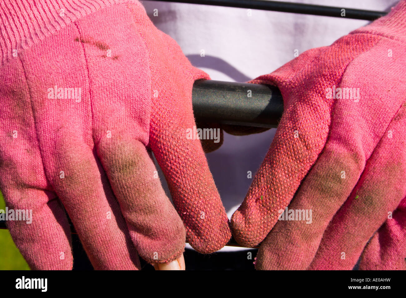Mujer vistiendo rosa guantes de trabajo descansando en manos cortadora de  césped manejar Fotografía de stock - Alamy
