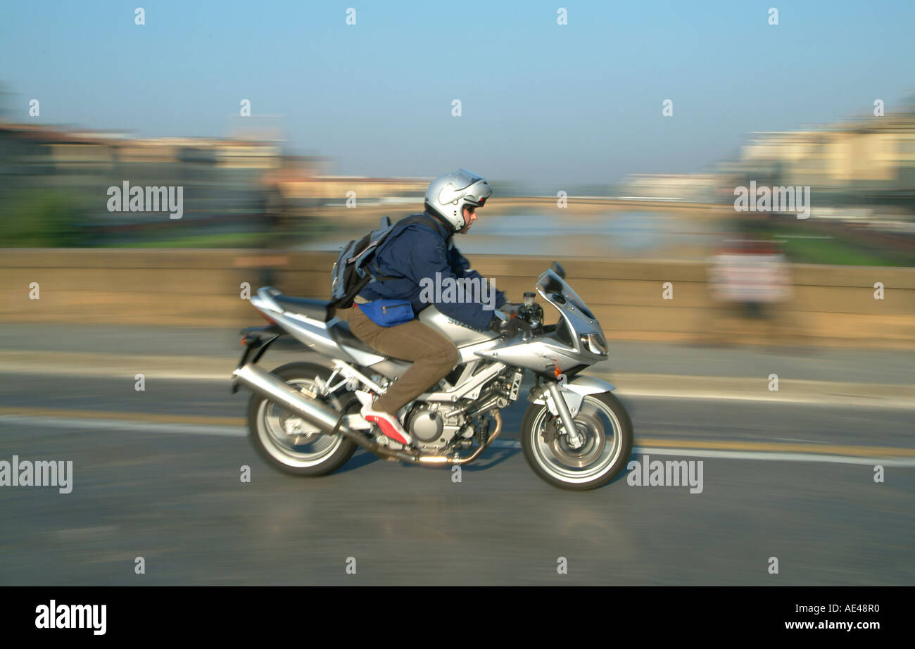 Persona que viajaban en una motocicleta Suzuki a través de un puente en Florencia Toscana Italia Foto de stock