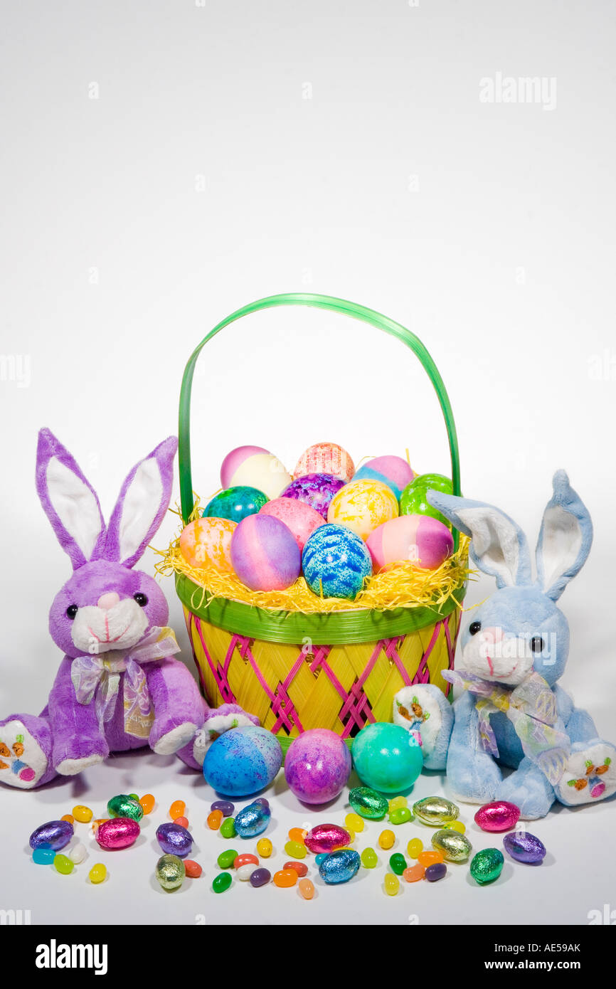 Paja cesta llena de Pascua con huevos coloreados con peluche conejitos de Pascua y caramelos de colores Foto de stock