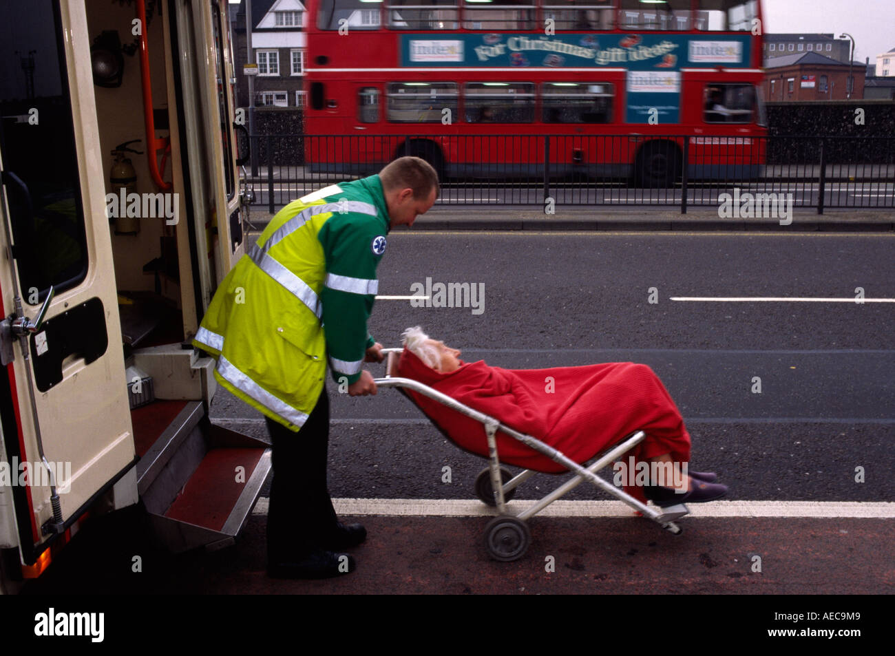 Londres tripulante de ambulancia levanta un viejo pensionista en una ambulancia después sintió indispuesto en su casa Foto de stock