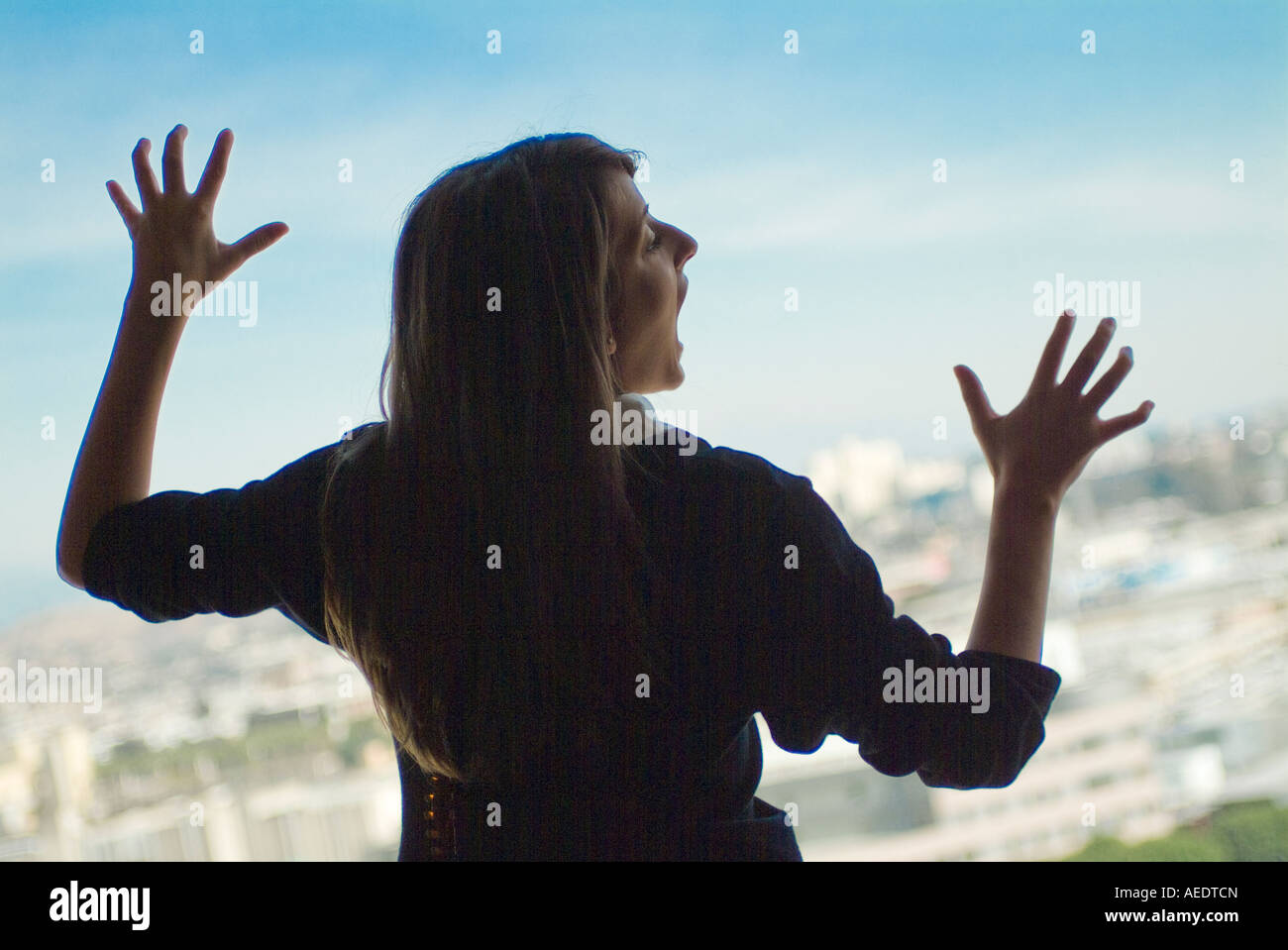 Mujer joven de pie en la ventana gritando Foto de stock