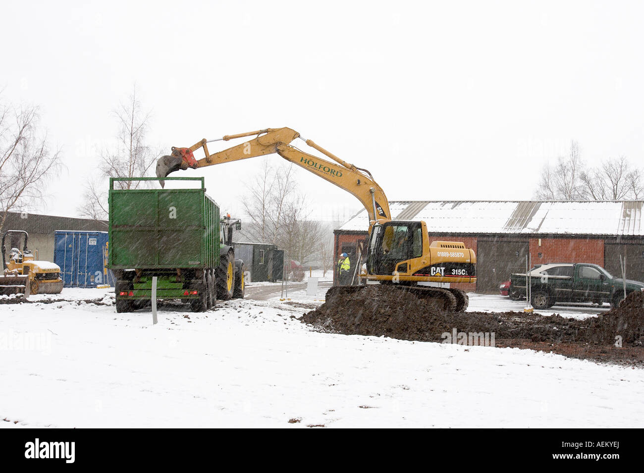 Una excavadora JCB trabaja en una obra en construcción en la nieve. Foto de stock