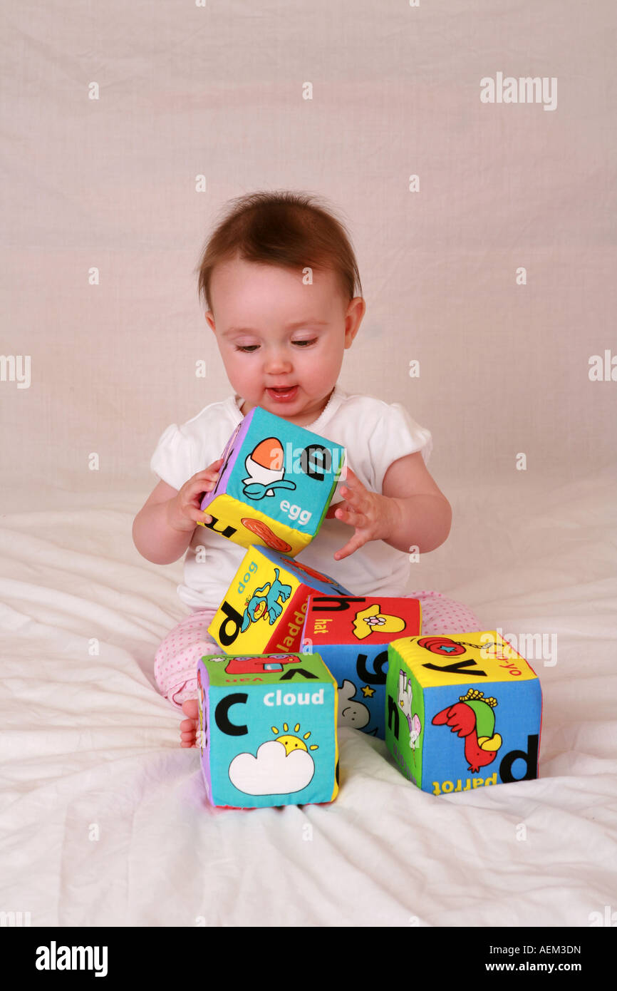 Inocente angelical bebé recién nacido a 7 meses de edad sentado jugando con  colores suaves juguetes de ladrillo del alfabeto alegre y contento  Fotografía de stock - Alamy