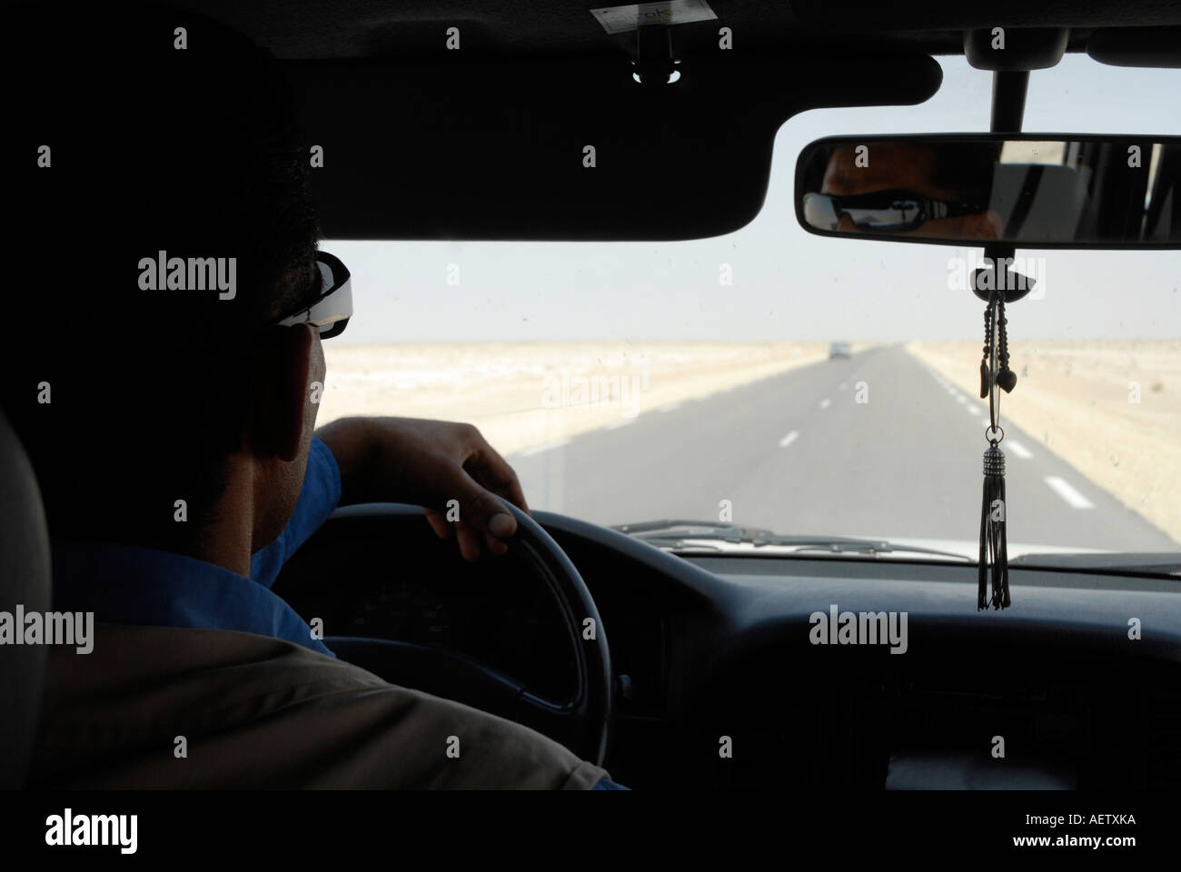 Outh mirando a través del parabrisas del vehículo a través de la conducción de Great Salt Lake, en el sur de Túnez Foto de stock