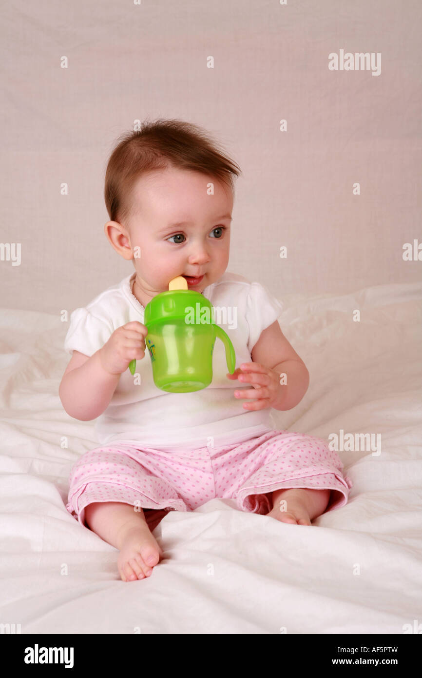 Niño recién nacido 7 meses bebiendo de verde lima, alimentación de bebés  taza taza vaso de precipitado mostrando habilidades de motor avanzado  Fotografía de stock - Alamy