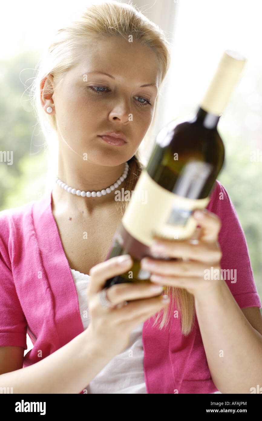 Mujer mirando su etiqueta en una botella de vino Foto de stock