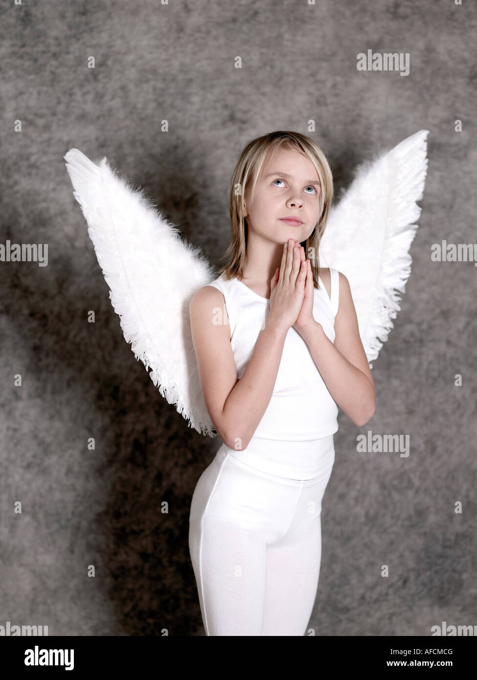 Niña vestidos en alas de ángel orando y mirando hacia arriba Fotografía de  stock - Alamy