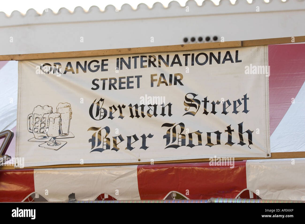 Calle signo alemán da la bienvenida a los visitantes del stand de cerveza sección de una feria al aire libre en naranja. Foto de stock