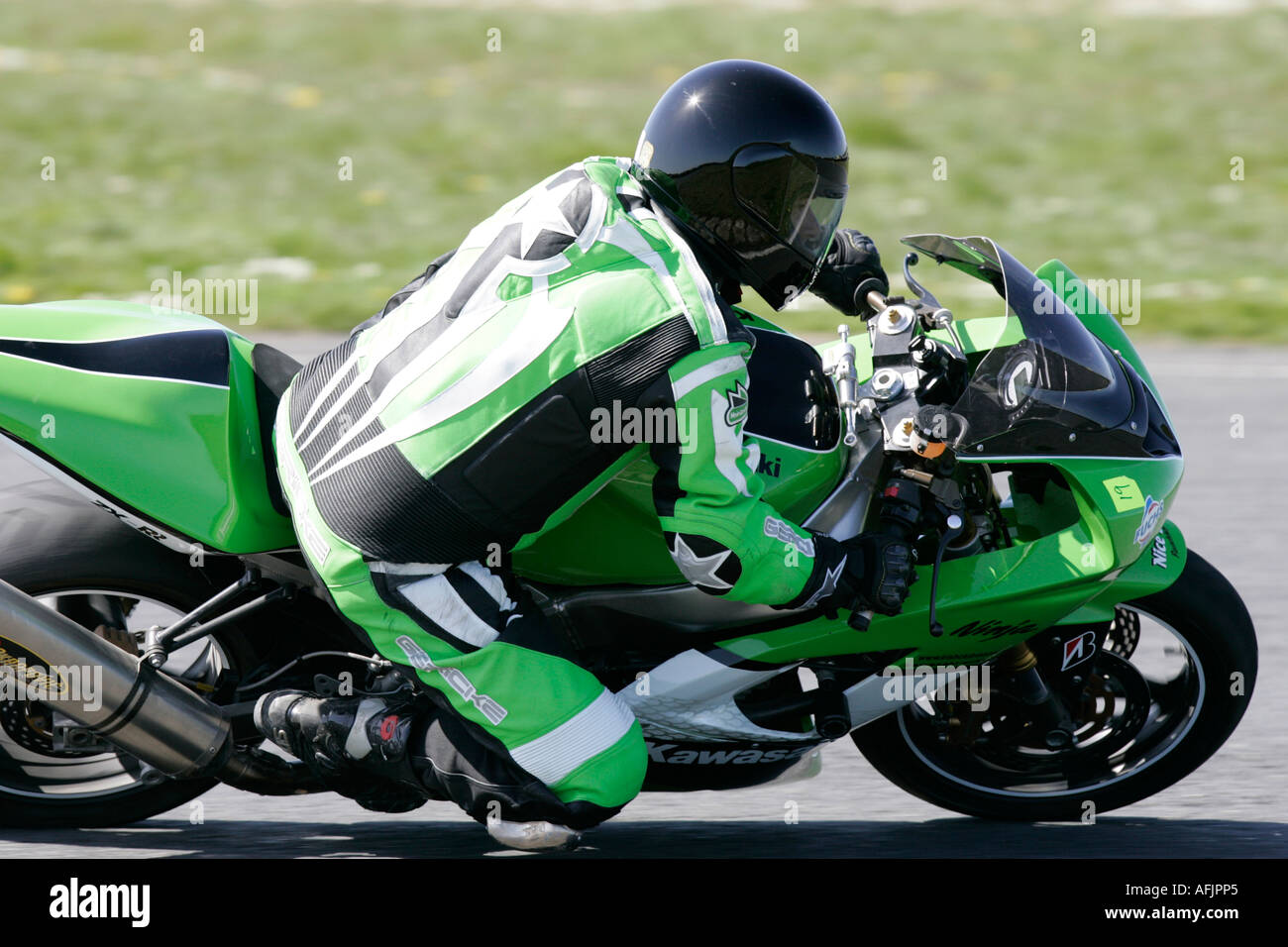 Jinete en verde cueros blancos y negros con casco negro sobre un verde kawasaki  ninja moto con la rodilla hacia abajo Fotografía de stock - Alamy