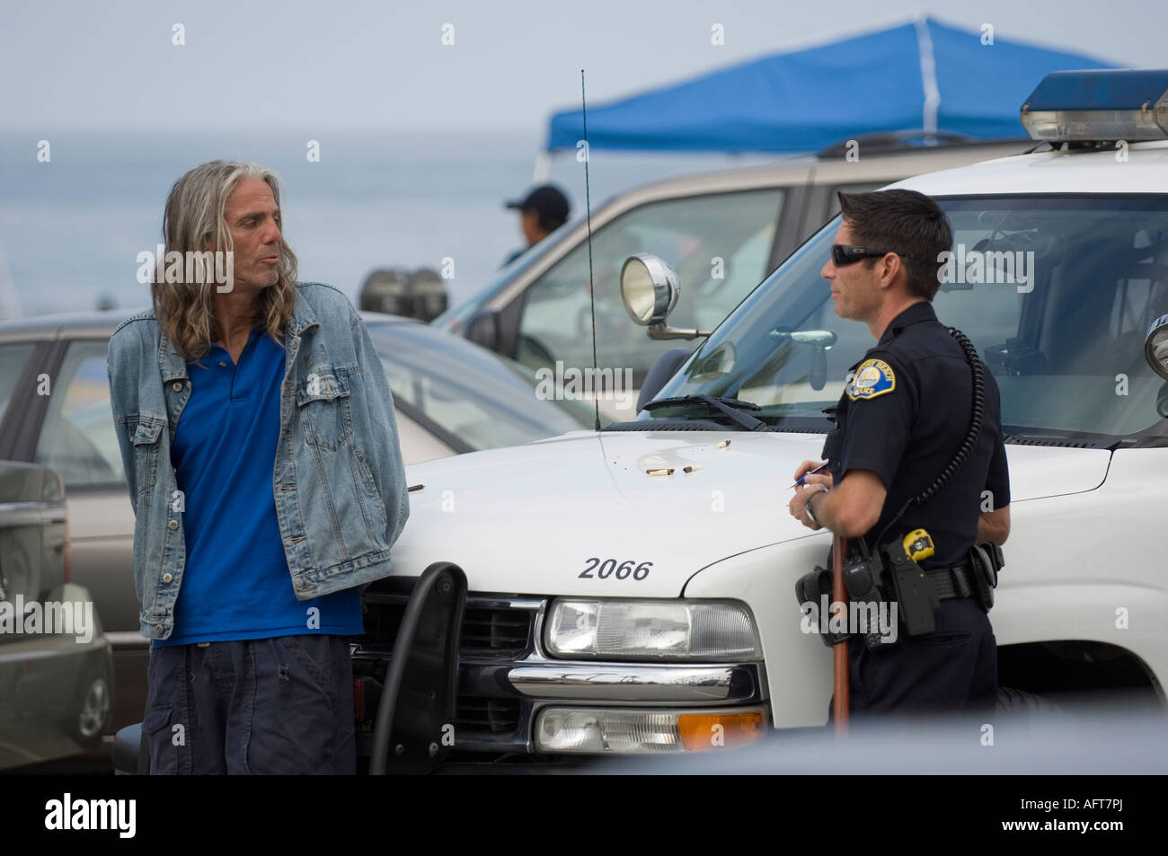 Hombre detenido e interrogado por la policía de Newport Beach. El capó del coche de la policía muestra materiales para fumar. Uso Editorial. Foto de stock