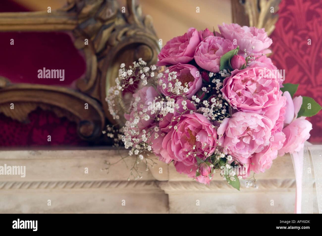 Novias posy estilo rosa ramo de peonías en mármol rojo chimneypiece contra William Morris papel tapiz Foto de stock