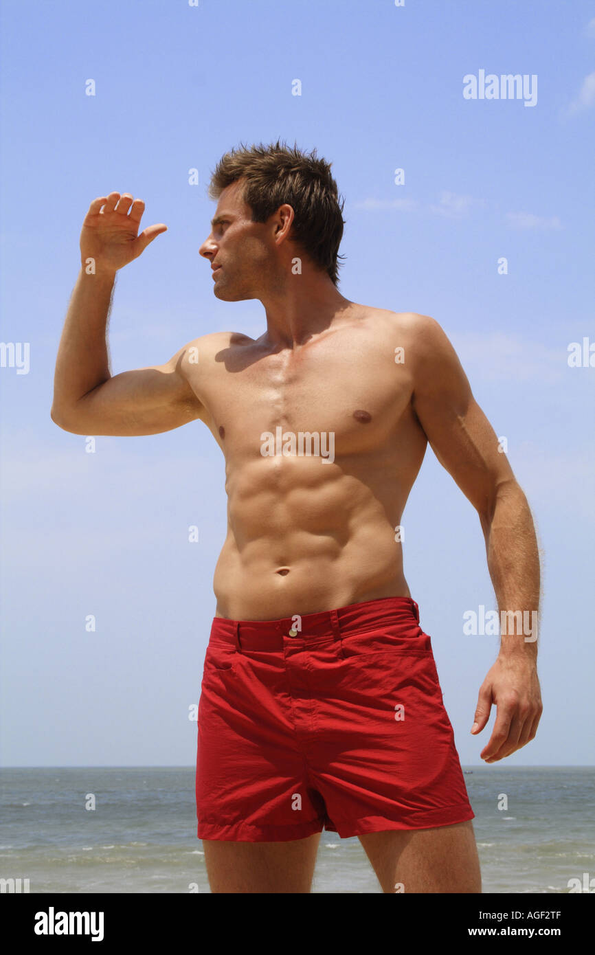 Hombre en playa en calzones rojos mirando al mar Fotografía de stock - Alamy