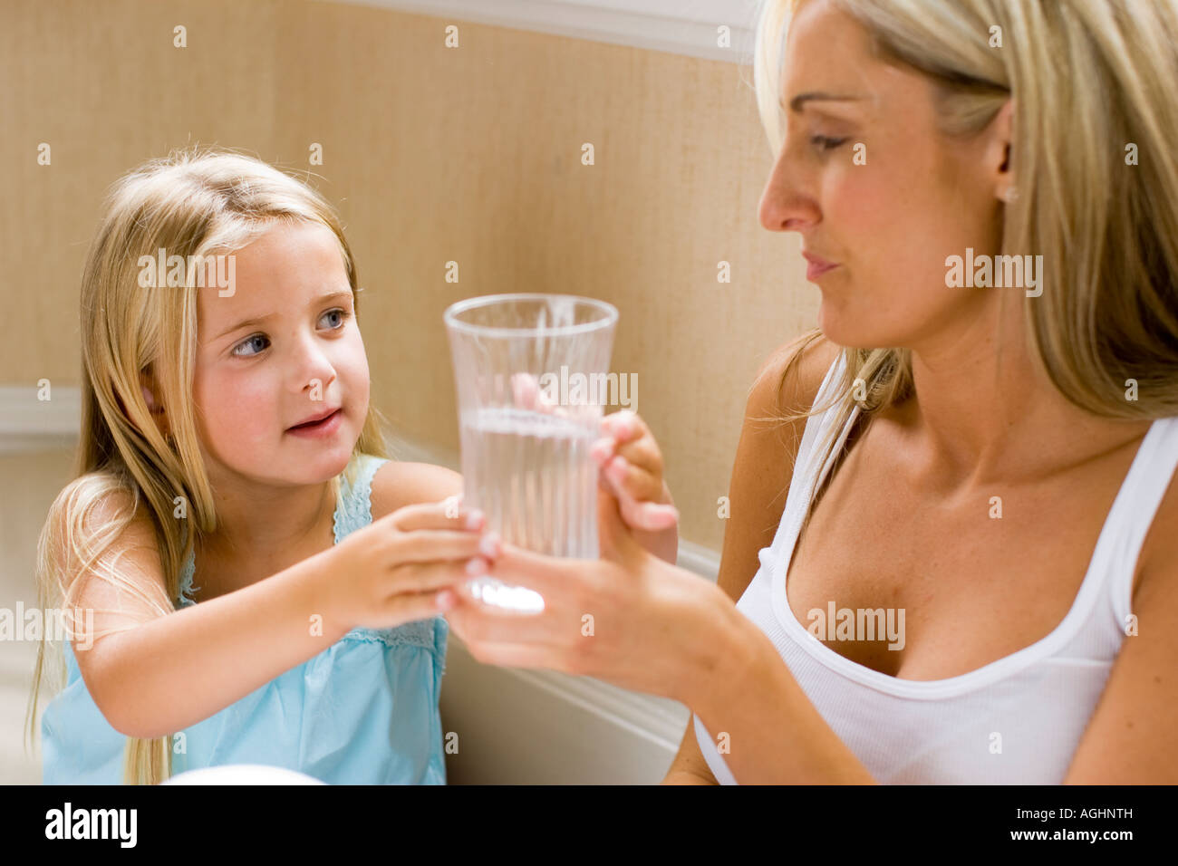 Madre dando a su hija a un vaso de agua. Foto de stock
