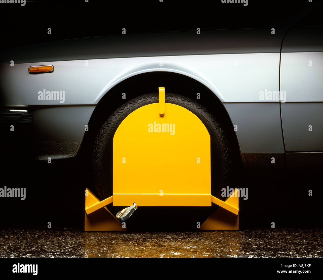 La abrazadera de la rueda de color amarillo en un coche de plata Foto de stock