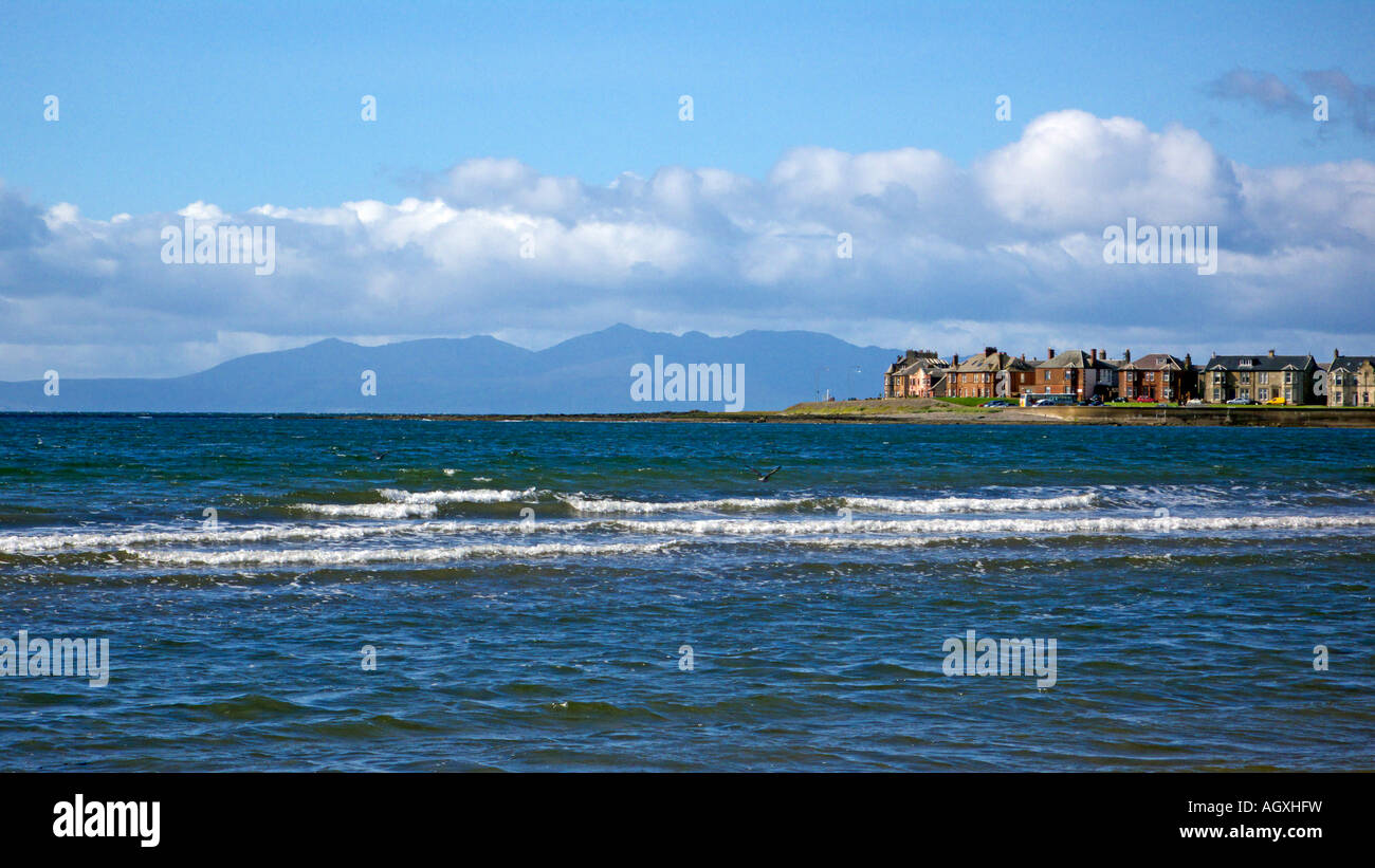 Vista desde la playa en Troon hacia el Arran colinas en la distancia con las olas rompiendo en la marea se mueve. Foto de stock
