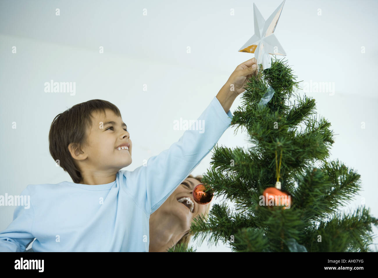 Niño y madre decorar árbol de Navidad, el chico colocando la estrella en la  parte superior del árbol Fotografía de stock - Alamy