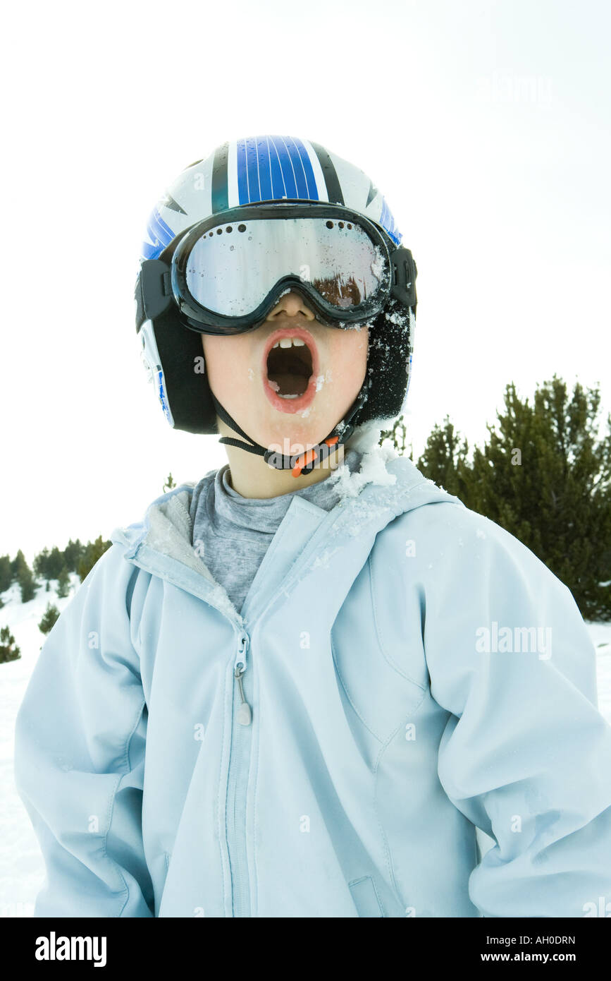 Niño con casco y gafas de esquí, cubiertos de nieve, boca abierta  Fotografía de stock - Alamy