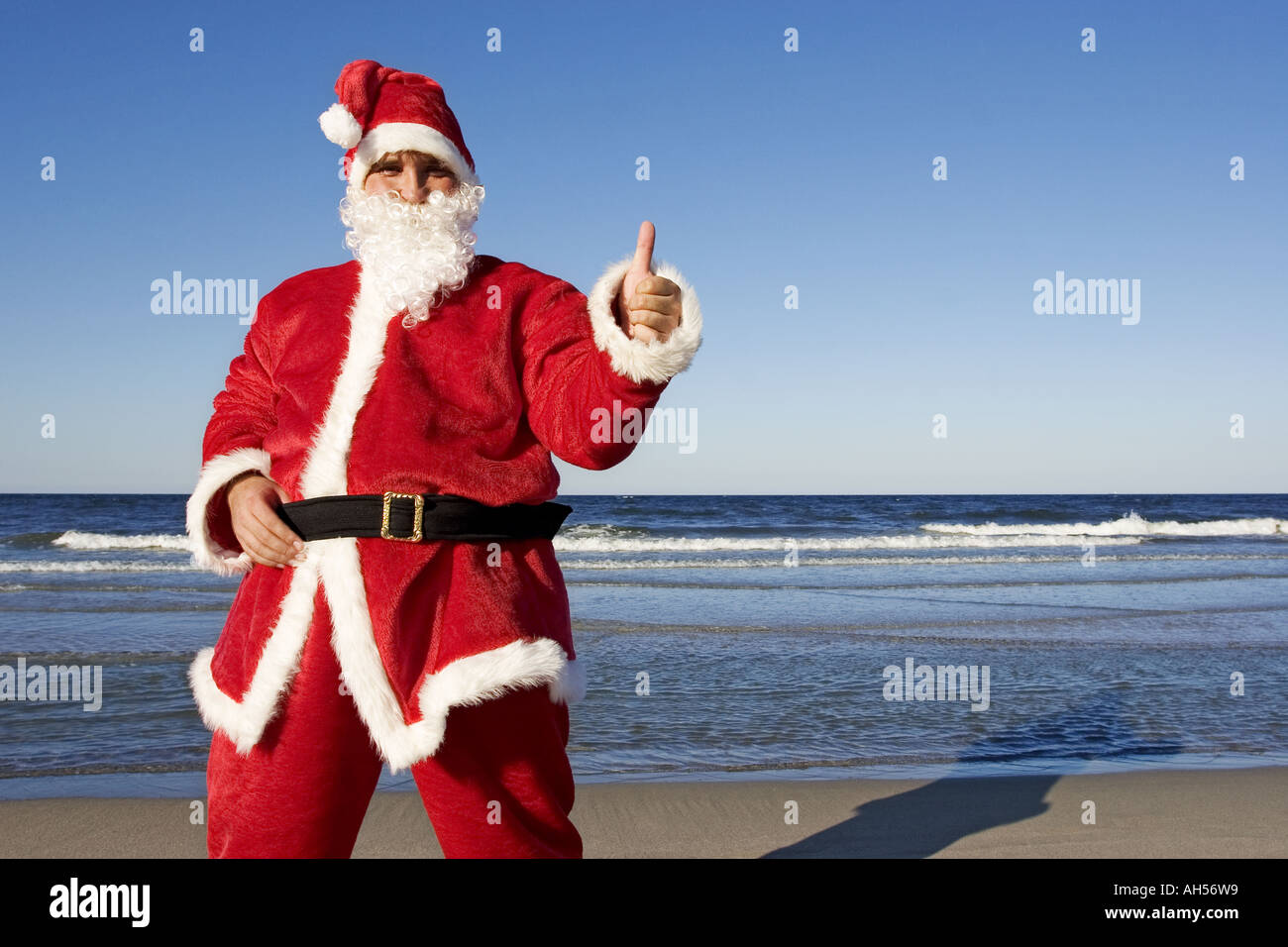 Día al aire libre con agua de mar en la playa de arena de verano vestido disfraz  santa claus cap pantalones Navidad tradición joven barba mano gest  Fotografía de stock - Alamy