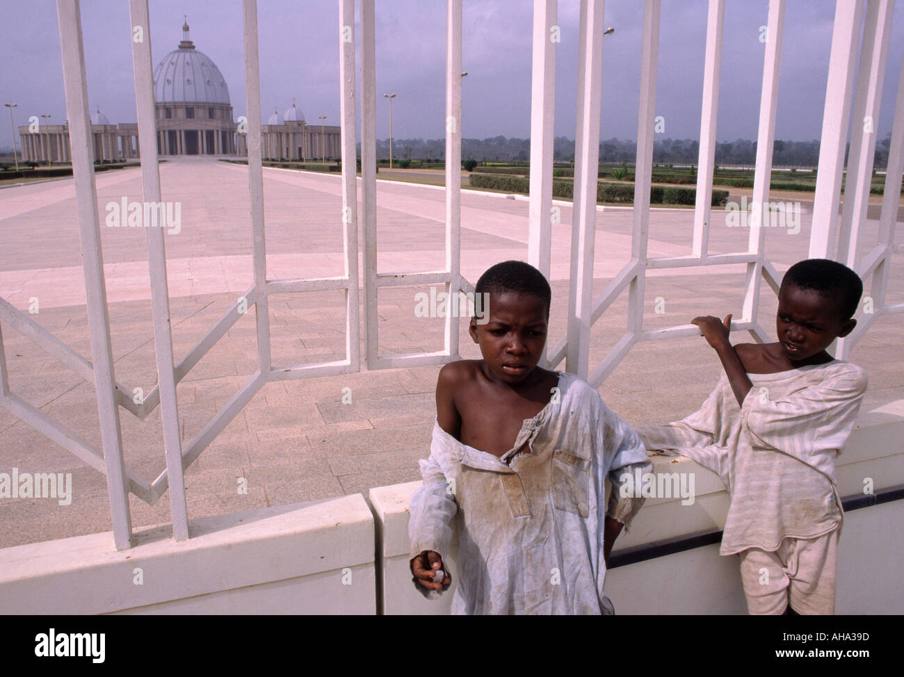 Dos muchachos adolescentes en ropa desigual pararse afuera de la puerta de la catedral de Notre Dame de la Paix Basílica en Yamoussoukro, Côte d'Ivoire Foto de stock