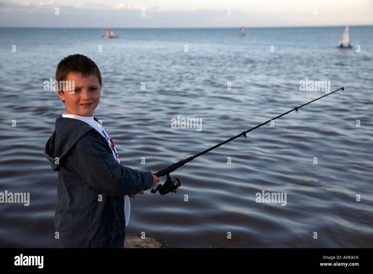 Joven muchacho de siete años en un muelle de pesca girado hacia la cámara en el condado de Wexford, República de Irlanda Foto de stock