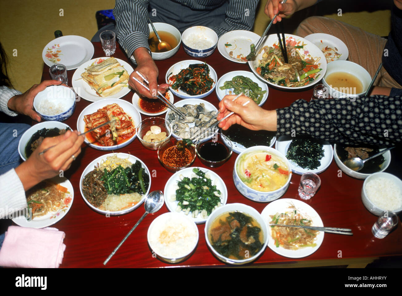 Familia sentado en mesa de comer varias comidas coreano hecho en casa. Foto de stock