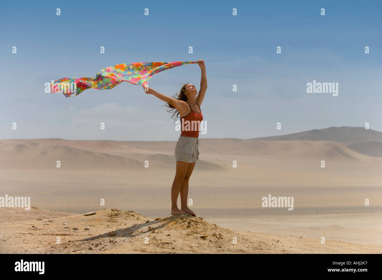 Una mujer sostiene un pañuelo al viento del desierto Foto de stock