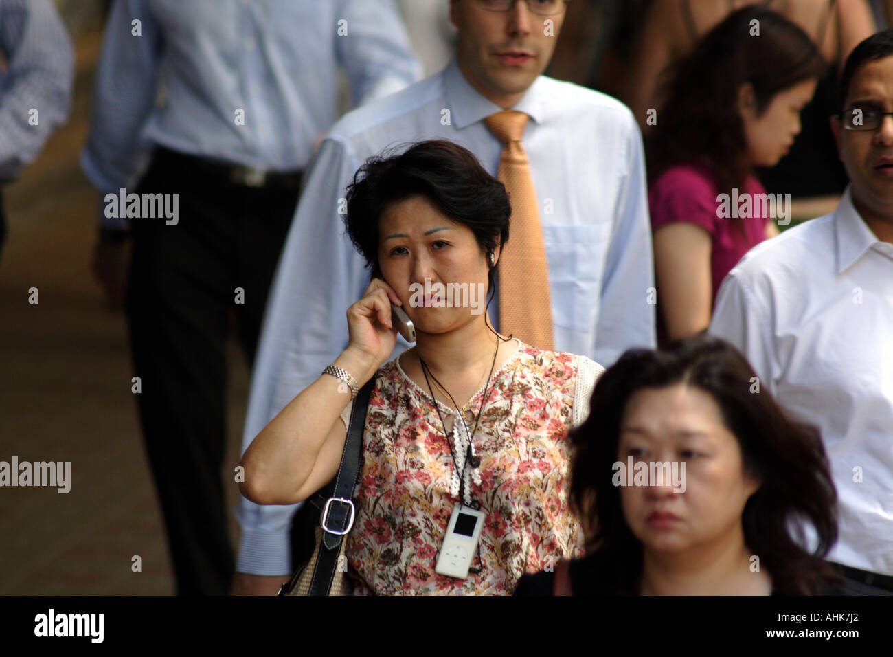 Mujer China hablando por un teléfono móvil y usando un IPod Nano en una  concurrida acera pública, Hong Kong Fotografía de stock - Alamy