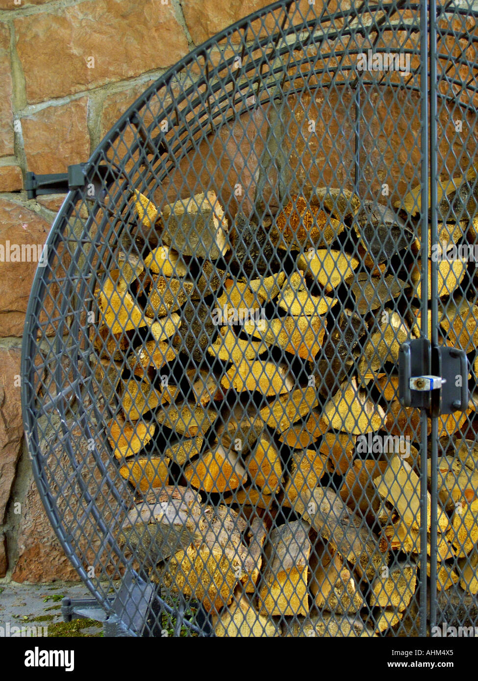 La leña apilada en una jaula de hierro de leña al aire libre contra una  pared de piedra laja roja Fotografía de stock - Alamy