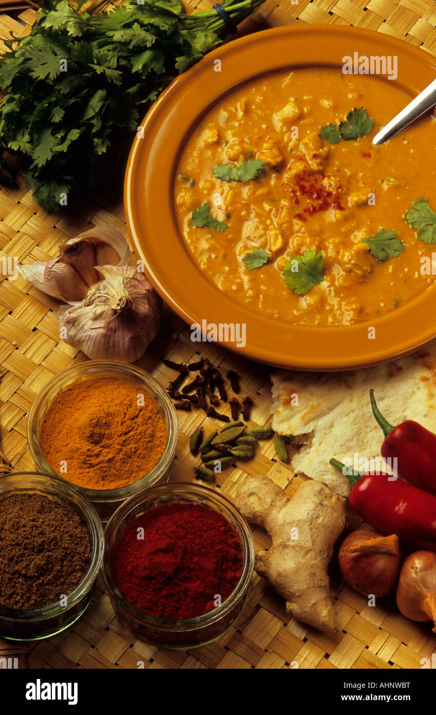 Un tazón de sopa mulligatawny picante rodeado de ingredientes de cocina india Foto de stock